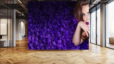 The girl in the petals. Beautiful young girl lies in the violet petals in a long dress. Glamor, luxe. Hair - curls. Makeup - arrows, purple lipstick. Love, romance. Wall mural