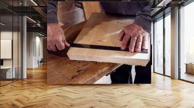 male carpenter marks out a wooden board with a ruler and pencil in his home workshop. working with wood. Wall mural