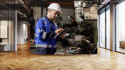 Male workers wearing uniform safety and hardhat  using tablet checking size an iron cutting machine in factory. Wall mural