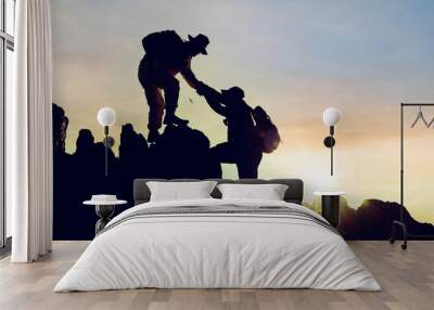 Silhouette climbing buddies help each other climb up the mountain at sunrise as the right lifestyle idea Wall mural