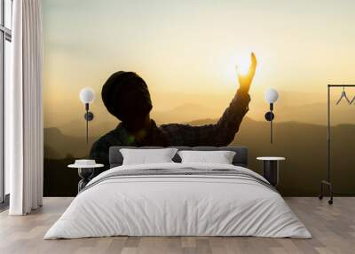 Silhouette rosary against cross in hand. Background sunrise Wall mural