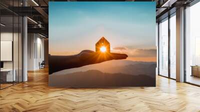 The man opened his hand and laid out a toy, a wooden house against the blue sky with sunshine. Wall mural