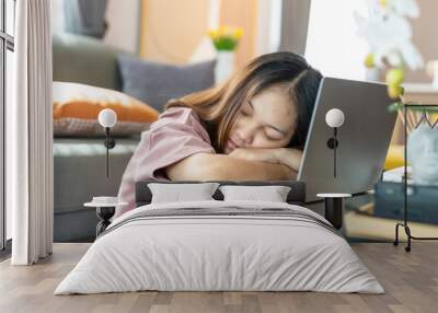 Asian woman with long hair is tired from sitting at work. and lay down in front of the notebook computer with exhaustion. sleeping in front of the laptop computer. Work from home. Wall mural