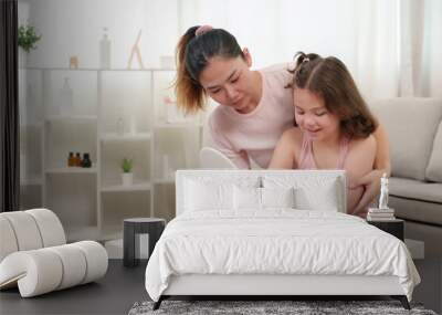 Mother helps young daughter with self-care routine, guiding application of skincare products. Both smiling warmly, bonding moment in modern home interior filled with natural light, enhancing intimacy. Wall mural