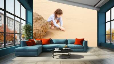 Five-year-old girl playing on the sandy beach of the sea Wall mural