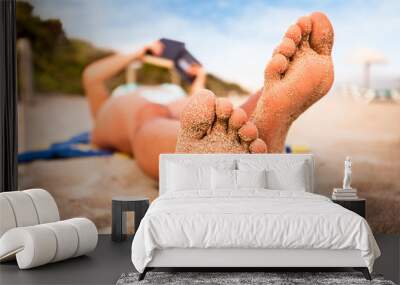 Woman reading a book on the beach. Wall mural