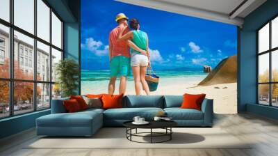 Couple in bright clothes on a tropical beach at Praslin, Seychelles. Wall mural