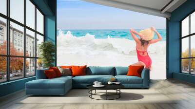 Young woman in red swimsuit and hat enjoying sunny day at tropical beach Wall mural