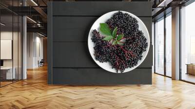 Ripe elderberry in plate on wooden black background Wall mural