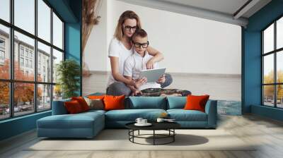 Young stylish child doing homework at home with  digital pad helped by his mother. Mum teaching his son. Education, family lifestyle, homeschooling concept. People  with glasses Wall mural