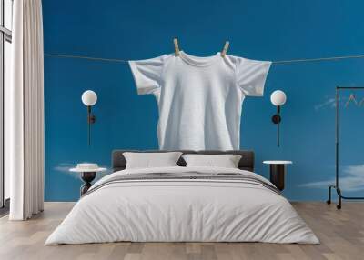 A white boys' T-shirt hangs on a clothesline against a blue sky backdrop. Wall mural