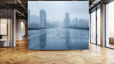 Rainy day scene featuring an empty wet asphalt road against a foggy city skyline background. Wall mural