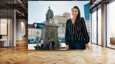 Smiling excited female tourist visiting Zagreb, Croatia. Walking tour sightseeing in the city centre. Croatian capital tourism.Exploring culture, visiting landmarks and attractions. Vacation in Europe Wall mural