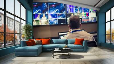 TV director at editor in studio. TV director talking to vision mixer in a television broadcast gallery.Man sat at a vision mixing panel in a television studio gallery Wall mural