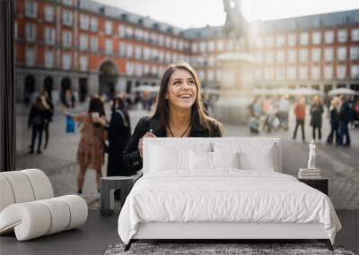 Young travel woman sightseeing urban outdoors.Traveling to Europe. Walking tour in Madrid.Backpack tourist experience.City girl.Cheerful tourist.Visiting Plaza Major square Wall mural