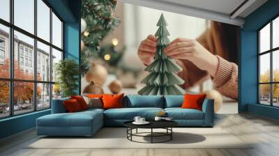 Child girl making a Christmas tree from green paper. Christmas traditions, children's leisure Wall mural