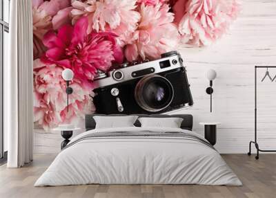 Vintage retro camera and a bouquet of peonies on a white wooden background. International day of the photographer Wall mural