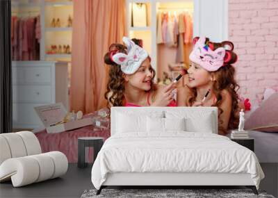 Children's pajama party. A teenage girl in pink pajamas, with makeup and pink curlers on the bed with makeup brushes is making up. Wall mural