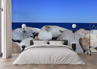 a clear sunny summer day by the sea or lake. big stones on the shore and blue clear sky. Wall mural