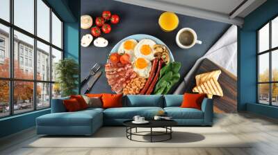 A traditional English breakfast of seven ingredients. Fried bacon, sausages, fried fresh tomatoes and champignons, white beans in tomato sauce, toast, fried eggs. Dark background. View from above. Wall mural