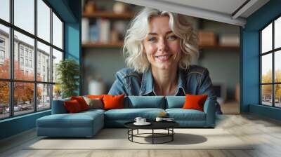 Smiling woman in a denim shirt radiating joy in a cozy indoor setting Wall mural