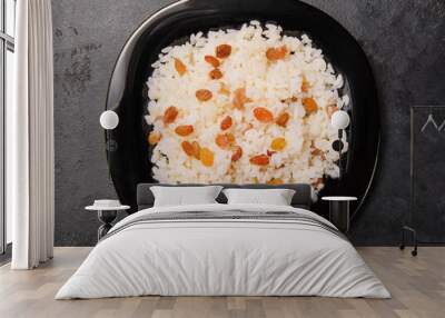 caucasian sweet pilaf with raisins on a black plate top view, Wall mural