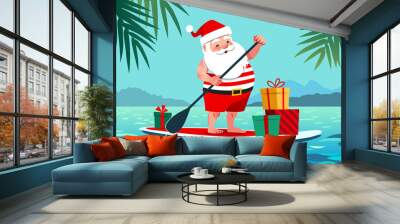 Cute Santa Claus in shorts and t-shirt on a stand up paddle board with gifts, against tropical ocean background with palm trees. Warm weather Christmas celebration, warm climate holiday vacation theme Wall mural