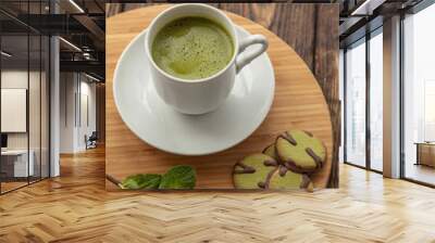 cup of Matcha tea and green cookies on a round wooden tray Wall mural