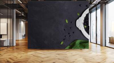 Fresh forest blueberries on a tin plate and green textile on a black background. Flatlay, top view, copyspace Wall mural