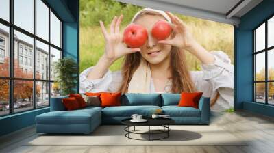 girl in a white shirt with 2 red tomatoes on a green background Wall mural