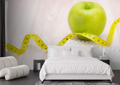 green apple, a measuring tape, notebook for writing on a light wooden background. preparation for the summer season and the beach, weight loss and sports concept Wall mural