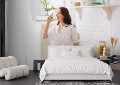 Gorgeous woman drinking water in her kitchen Wall mural