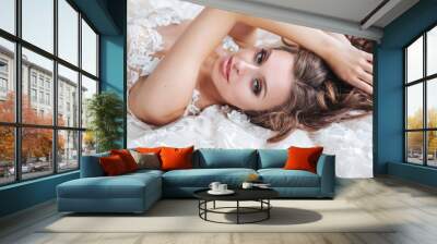 Beautiful bride is lying on a white bed in the hotel. The girl in a white dress is resting in the bedroom Wall mural