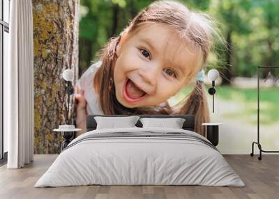 Close-up portrait of an excited little girl laughing in park Wall mural