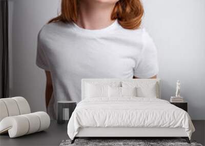 Redhead smiling little girl model posing in white t-shirt on grey background Wall mural