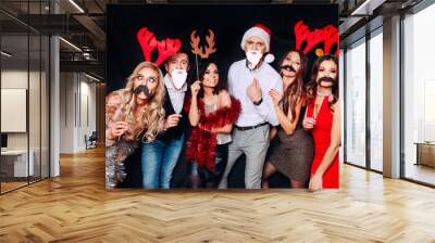 Six young funny friends, four girls and two boys while celebrating Christmas. Group of friends at club having fun. New year's party Wall mural