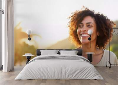 Lifestyle portrait of happy black woman with curly hair on vacation walking on tropical island beach at sunset Wall mural