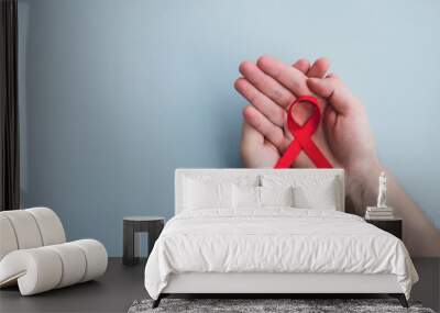 Man hands hold red ribbon awareness Aids on a light blue background. Medicine concept, World Aids day campaign. Top view, copy space Wall mural