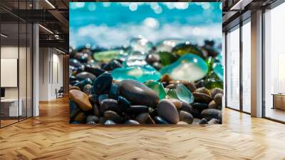 Natural polish textured sea glasses and stones on the seashore. Azur clear sea water with waves. Green, blue shiny glass with multi-colored sea pebbles close-up. Beach summer background Wall mural