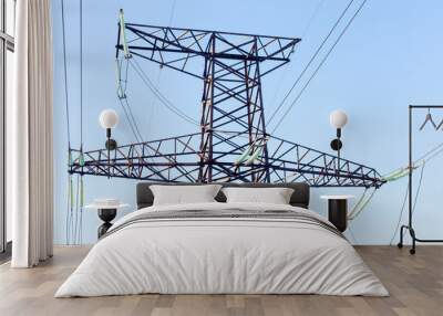 Power lines. High voltage power pylons against blue sky and sun rays Wall mural