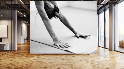 Classical black and white Art Photography of a woman practicing advanced yoga pose indoors on a yoga mat.  Woman's dynamic arms in Downward Dog. Wall mural