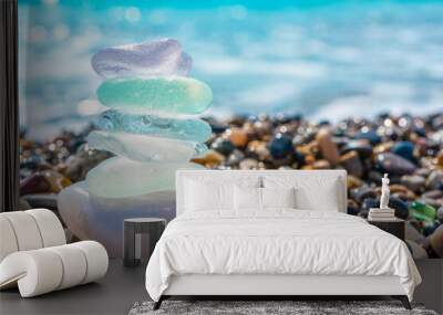 Sea glass stones arranged in a balance pyramid on the beach. Beautiful azure color sea with blurred seascape background. Meditation and Harmony concept. Wall mural