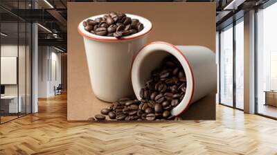 Two white porcelain cups with coffee beans. One cup is upset. Wall mural