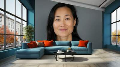 Studio headshot of mature professional Asian woman wearing business suit, gray background Wall mural