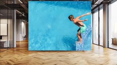 Summer active water fun on vacation. Boy child jumping into the pool. Wall mural