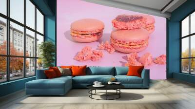 Tasty pink raspberry macarons on light violet background. French homemade dessert with small broken pieces Wall mural