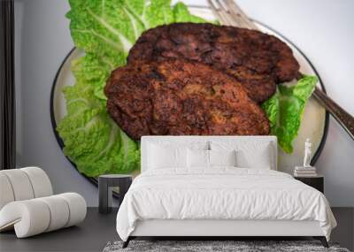 The sound of two cutlets of beef liver and lettuce, a plate on a white background Wall mural