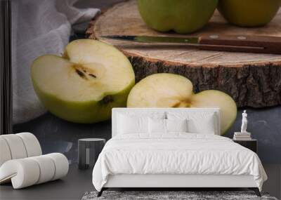 Two green golden apples cut in two halves on a wooden platter. In the background are whole apples. Wall mural