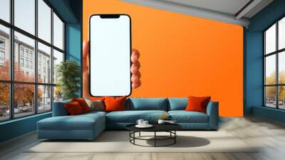 Mockup of hand holding smartphone with blank screen. Colorful orange banner with copy space. Wall mural