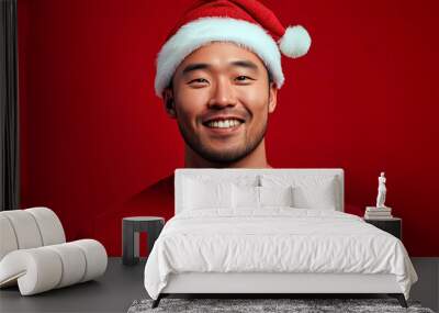 Portrait of happy asian man wearing christmas santa hat over blue background. Wall mural